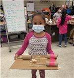 student with marble run created with toilet paper tubes, cardboard, and craft sticks